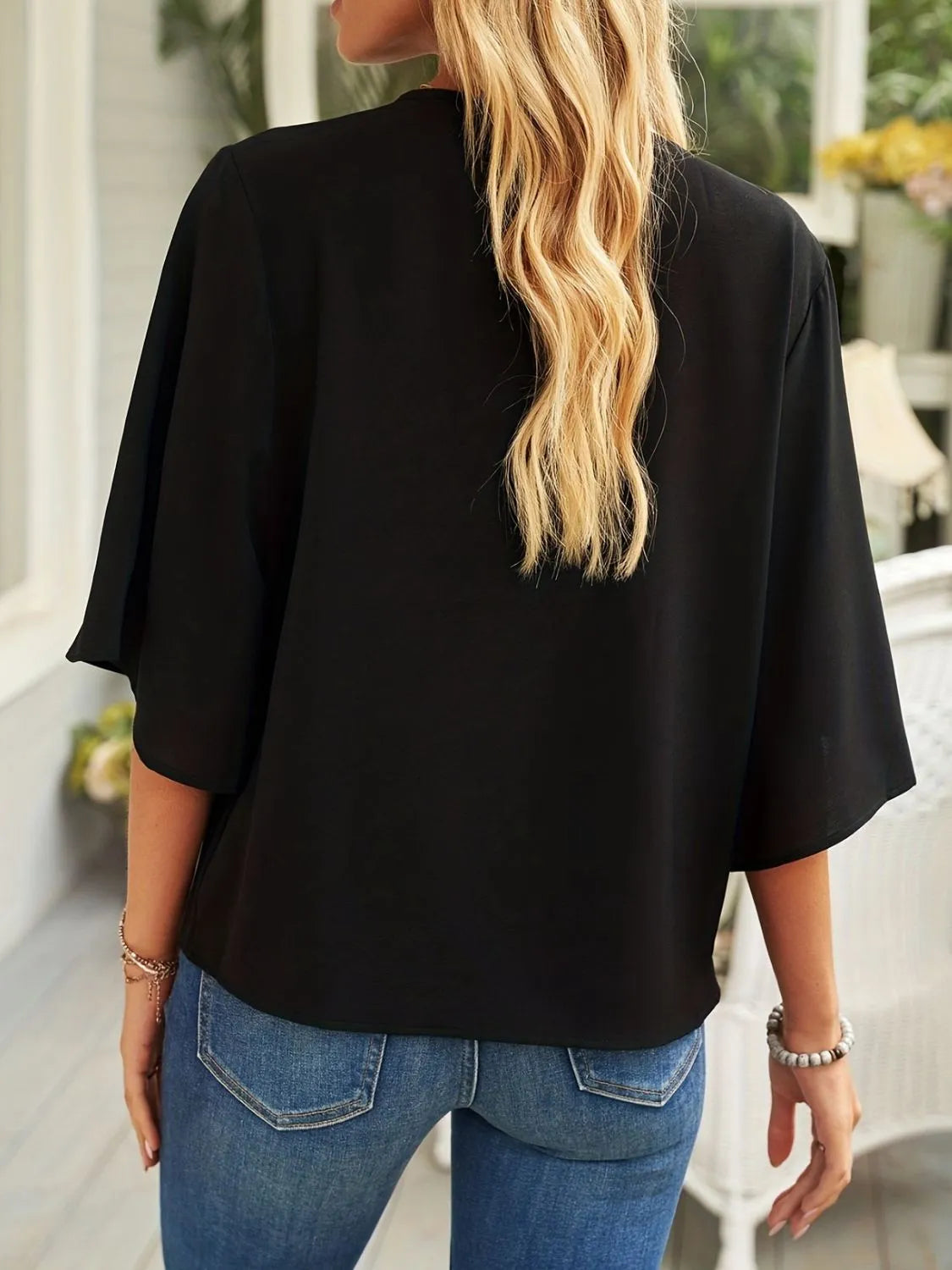 Black three-quarter sleeve blouse for women shown from the back with loose fit and casual style