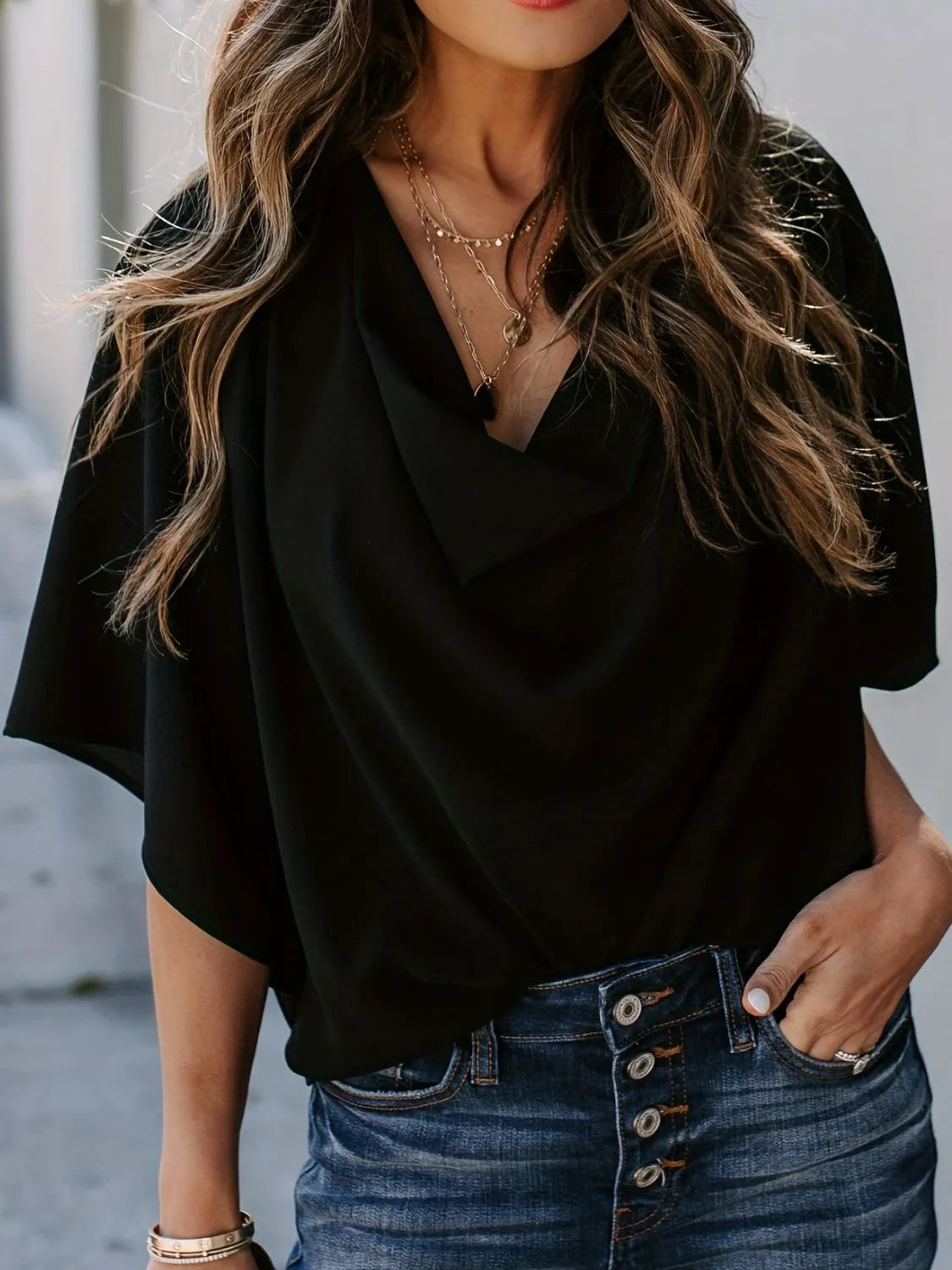 Black three-quarter sleeve blouse for women styled with layered necklaces and blue button-up jeans