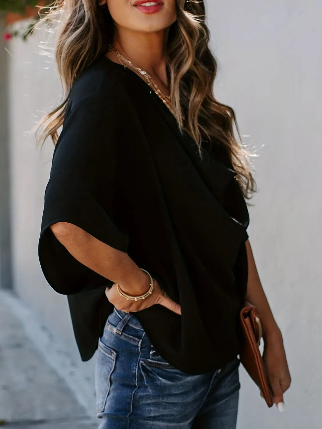 Black three-quarter sleeve blouse for women paired with blue jeans and accessories