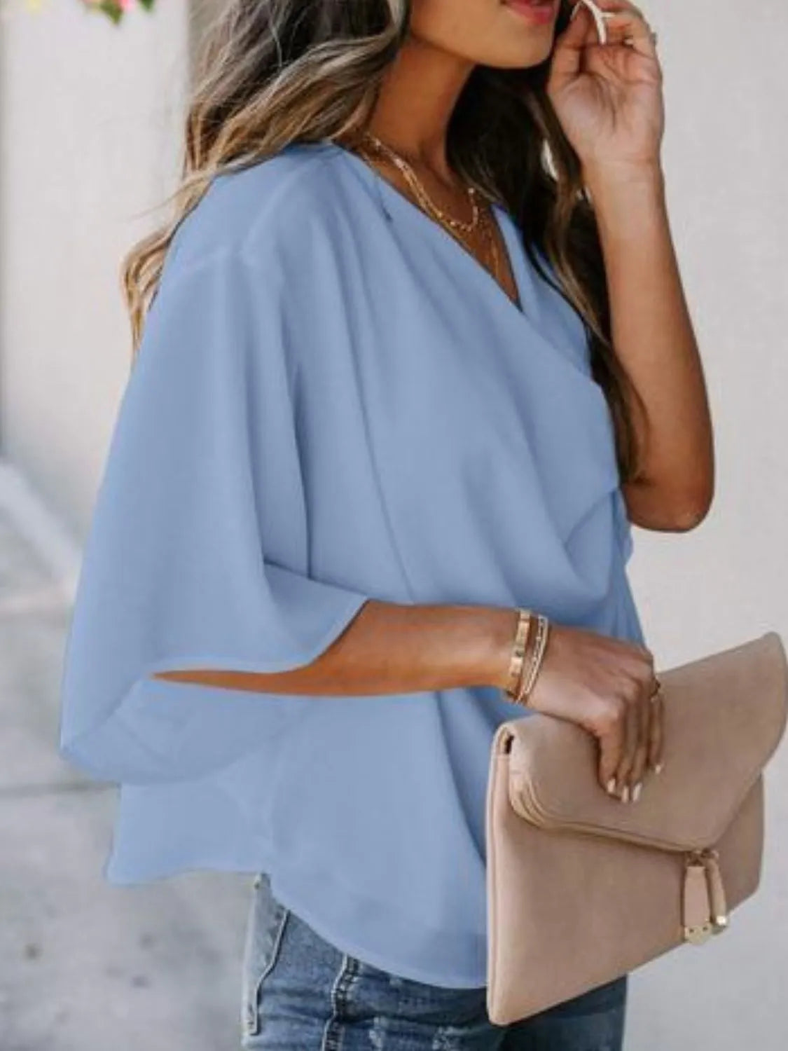Trendsi light blue three-quarter sleeve blouse for women with V-neck styled with gold jewelry and tan clutch